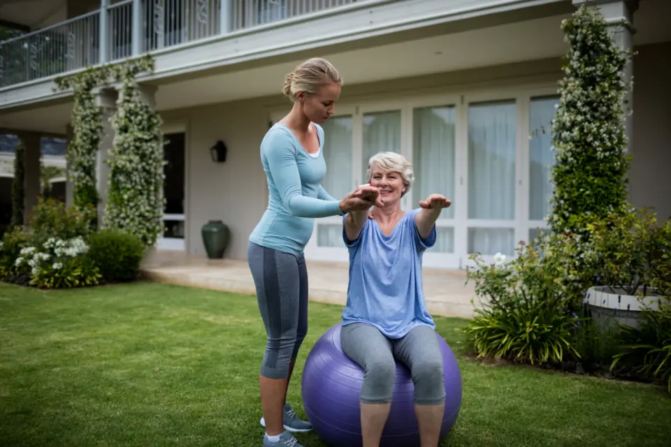 Therapeutin macht mit einer Seniorin Übungen im Garten